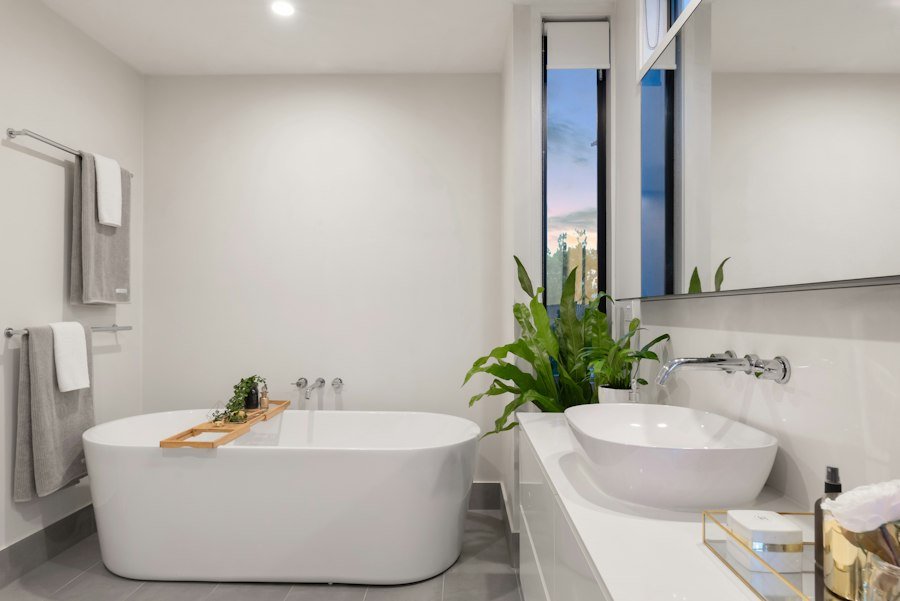 Baño reformado con bañera blanca y planta