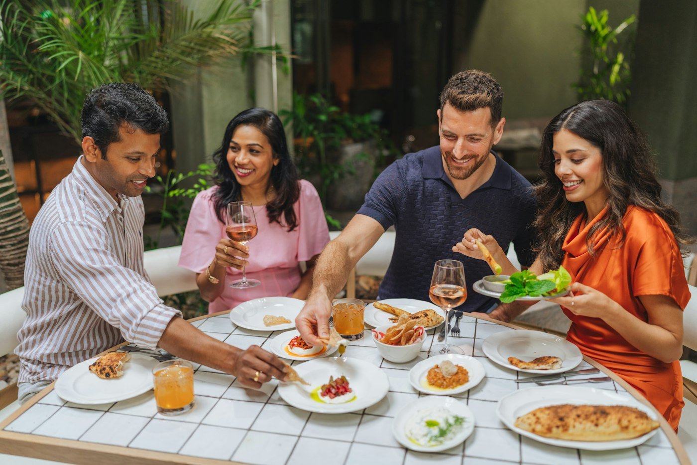 Amigos compartiendo platos pequeños y bebidas en la mesa de un restaurante