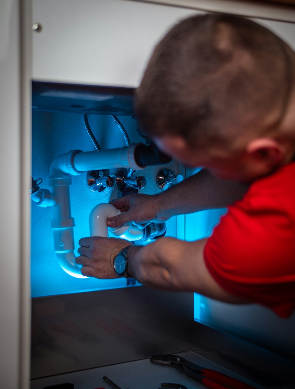 Instalador trabajando en una tubería bajo un mueble